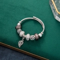 Vista macro di bracciale in filo d'argento con perline e un ciondolo a foglia cava - Foglia