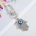 Silver Hamsa Hand keychain with blue evil eye and sparkling rhinestones on white backdrop - Medium Silver Hamsa Hand