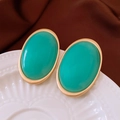 Macro shot of vintage oval earrings with emerald green inlay and matte gold finish - Silver Earring Post-Blue