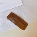 Detail einer dunkelbraunen Kunstleder-Haarspange mit feinen Nähten und rechteckiger Form - Quadratisch / Kaffeebraun