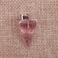 Makroaufnahme von facettiertem rosa Kristallanhänger auf strukturiertem Leinenhintergrund - Transparentes Rosa
