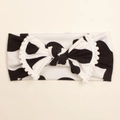 Soft baby headwrap featuring cow print with a large bow and white pom-pom trim detail - Style E (Black White Cow Print)
