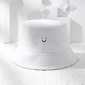 Close-up of white bucket hat featuring black embroidered smiley face and stitched brim - One Size / White