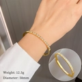 Brazalete minimalista de acero de titanio dorado con circonitas redondas y patrón geométrico - Dorado