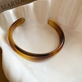 Détail d'un bracelet ouvert en résine écaille de tortue sur un plateau en coquillage blanc - Style Rond Café (1#)