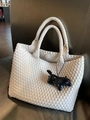 Detailansicht einer weißen Web-Tasche mit schwarzem Hunde-Anhänger auf einem Ledersessel - Cremeweiß (Kein Anhänger)