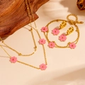 Elegant stainless steel gold jewelry set with pink daisy flower charms on beige linen - Pink Shell Set (L504-L506-L708)