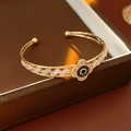Detail of gold open bracelet featuring blue crystal evil eye and rectangular zircons - Cuff Bracelet / Gold
