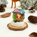 Close-up of a miniature Christmas resin house with glowing light and Santa figurine - Blue Roof House