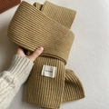 Close-up of camel-colored ribbed knit texture and h.modmi brand tag on winter scarf - Khaki