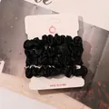 Set of 4 black satin scrunchies displayed on a white card against a warm background - Black