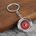 Detail of silver and red mesh wheel rim keychain on rustic wood and stone surface - Silver White + Red
