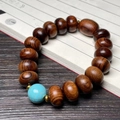 Sandalwood beaded bracelet featuring concentric wood grain and a blue turquoise centerpiece - 15mm Abacus Bead With Turquoise