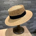 Detail eines natürlichen Boater Strohhuts mit schwarzem Band auf einem Holzständer - M (56-58cm) / Khaki Mit Schwarzem Band