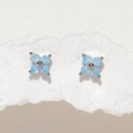 Detailed shot of light blue four-leaf clover stud earrings with opal texture on white paper - Blue Flower Silver Stud Earrings