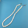 Detail view of a white heart-shaped bead necklace with a metal lobster clasp and chain - 6mm Heart Shape Shell Necklace