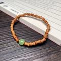 Bamboo shaped sandalwood bracelet with green jade bead and golden spacers on dark wood - Sandalwood 5x7mm Bamboo Joint with Green Jade Style Bead
