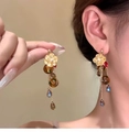 Detail of amber resin drop earrings with gold floral studs and pearl accents on model - Gold Red Coffee Flower Tassel