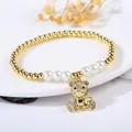Macro detail of gold-plated bear charm bracelet with pearls on decorative dish - Head and Paws Pave Bear