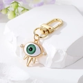Dettaglio del portachiavi Occhio di Allah dorato con pupilla verde e piccoli cristalli - Malocchio Verde (Tre Punte) / Oro