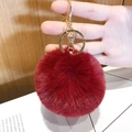 Dark red fluffy faux fur heart keychain with gold clasp held in hand for scale - Small Wine Red Pom Pom