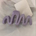 Detailed view of a purple wavy hair claw clip on a white branded display card - Purple