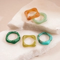 Dettaglio di 5 anelli geometrici in resina acrilica con texture marmorizzata su pietra - Set con Zirconia Verde