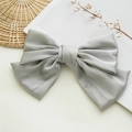 Barrette à cheveux avec grand nœud en satin gris posée sur un livre au style élégant - Gris