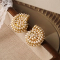Dettaglio macro di orecchini di perle dorate a forma di conchiglia su sfondo di tessuto - Gold Pearl Conch