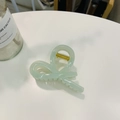 Detail of light green bow hair claw clip with gold spring on a clean desk - Jelly Cyan