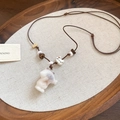 Détail d'un collier pendentif chat fait main avec perles en bois et corde tissée - Collier-Marron-Blanc-Chat