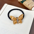 Coletero de mariposa ámbar con strass sobre una página de libro antigua - Coletero / Naranja
