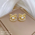 Detail view of pearl bow earrings on a leather box with size and weight specifications - B422 Stud Earrings (Silver Pin + Copper Gold Plated)