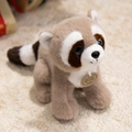 Cute plush raccoon toy with soft brown fur and blue eyes on a fluffy white rug - Raccoon