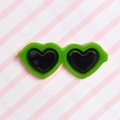 Detail of bright green heart-shaped pet glasses accessory on a striped background - Green