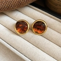 Vue rapprochée de boucles d'oreilles en résine ambre et métal doré sur présentoir - Rond