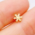 Macro shot of gold snowflake stud earring held between fingers for size reference - Gold Snowflake
