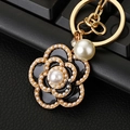 Golden camellia flower keychain with black enamel petals and white faux pearl accents - Black Camellia Pearl Keychain