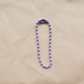 Close-up of a 2.4mm purple metal bead chain with connector on textured paper background - Purple
