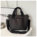 Detail of black nylon tote bag featuring adjustable strap and front snap pocket - Black