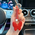 Detailed close-up of a red crystal butterfly keychain with a sparkling leather strap - Red