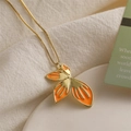 Minimalist gold chain necklace with orange enamel leaf pendant on elegant fabric base - Orange