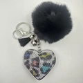 Detail of black plush ball keychain with a colorful rhinestone leopard heart and silver tassel - Rainbow