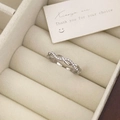 Macro shot of silver twisted infinity ring with zircons in a beige velvet jewelry box - Adjustable Open / Silver