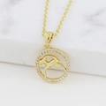 Macro detail of gold Capricorn necklace featuring a round pendant with pink zircons - Capricorn