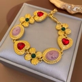 Dettaglio di un bracciale vintage dorato con cuori rossi e cammei su una scatola porta gioie - Bracciale - Oro