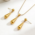 Poliertes goldenes Schmuckset mit Wassertropfen-Anhänger und passenden Ohrringen auf weiß - Halsketten- und Ohrring-Set / Gold