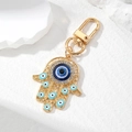 Macro shot of golden Hamsa Hand keychain with blue evil eye and sparkling rhinestones - Gold with Lake Blue Eye Style
