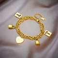 Zweilagiges goldenes Kettenarmband mit Herz- und Schlossanhängern auf Seidenhintergrund - Gold