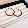 Detailed view of Ancora red twisted hoop earrings on white velvet jewelry display box - Red (Style 2 Deep Red Lacquer)